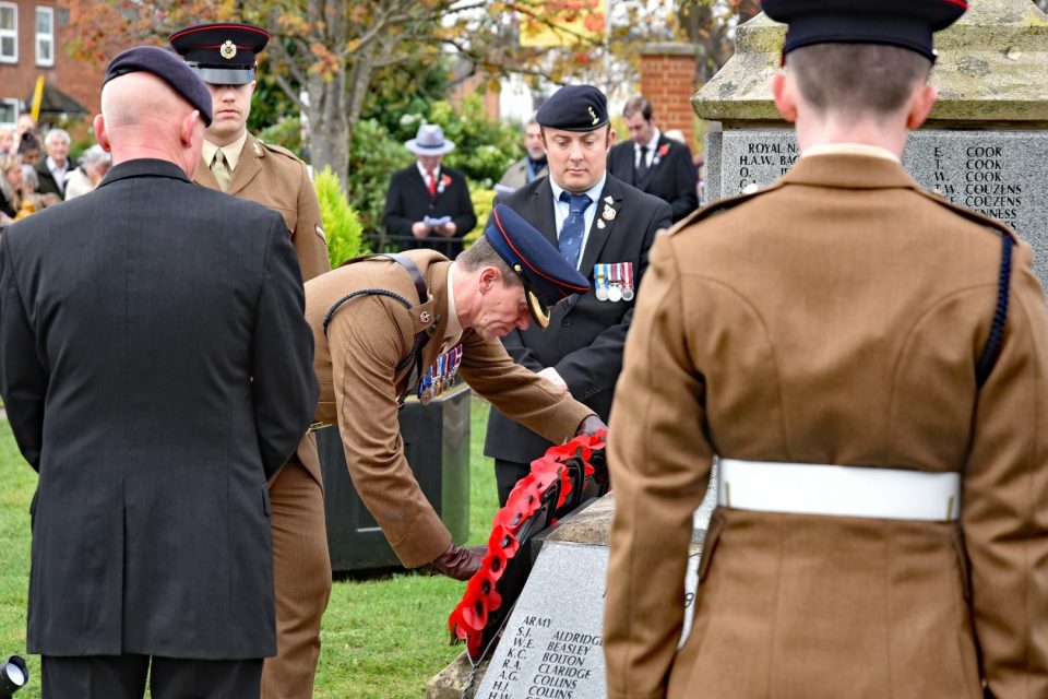 A soldier in uniform laying a poppy wreath at the war memorial