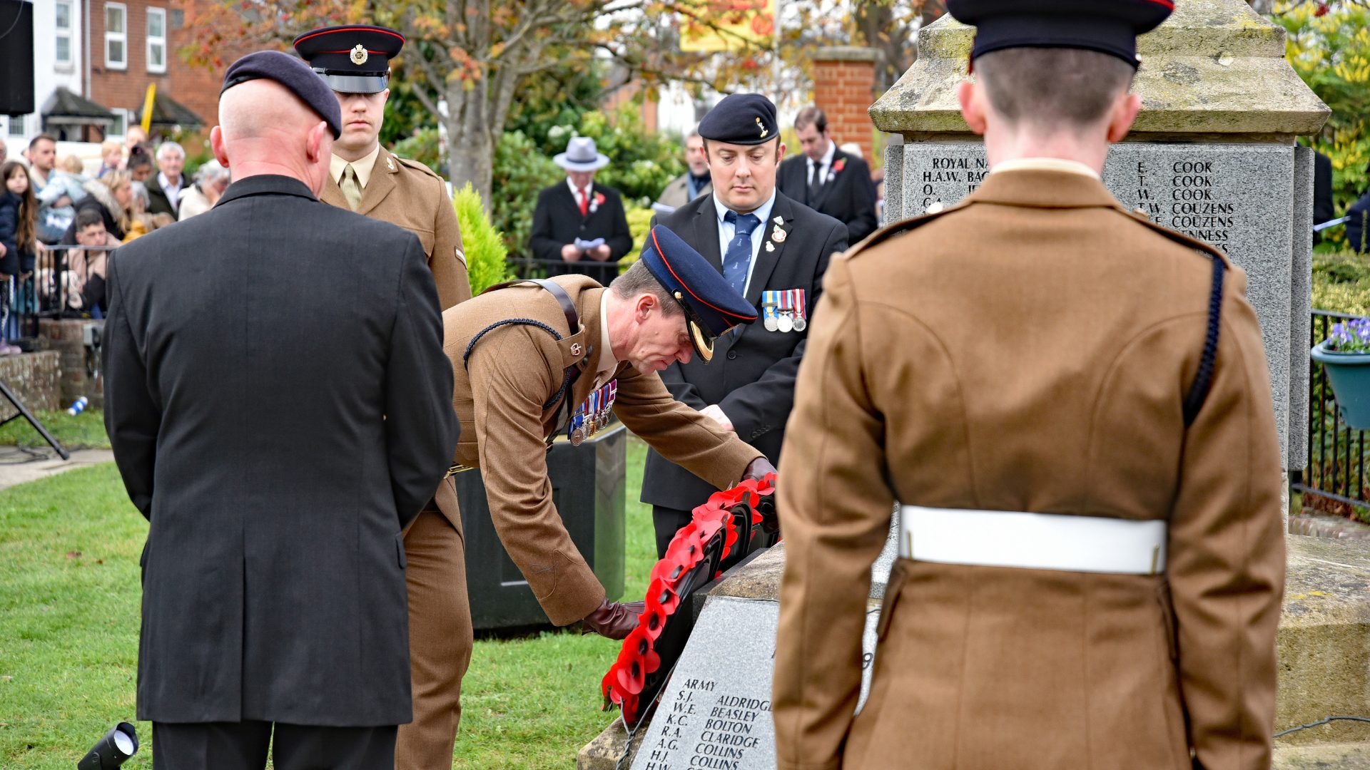A soldier in uniform laying a poppy wreath at the war memorial