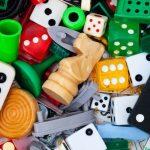 A pile of colourful dice, dominos, chess pieces and other game pieces