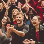 A group of young adults clapping and smiling