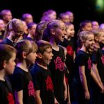 A photograph of children singing wearing Vox Fresh t-shirts