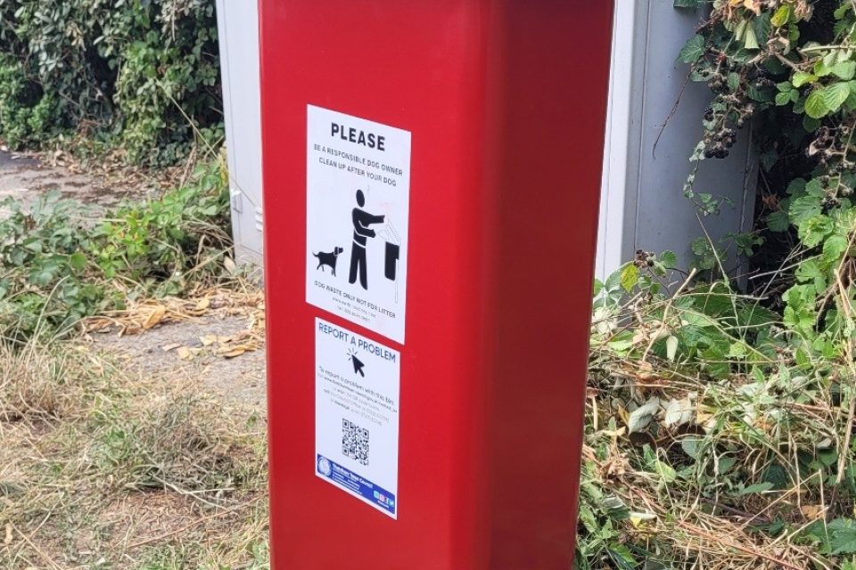 A large, red dog waste bin
