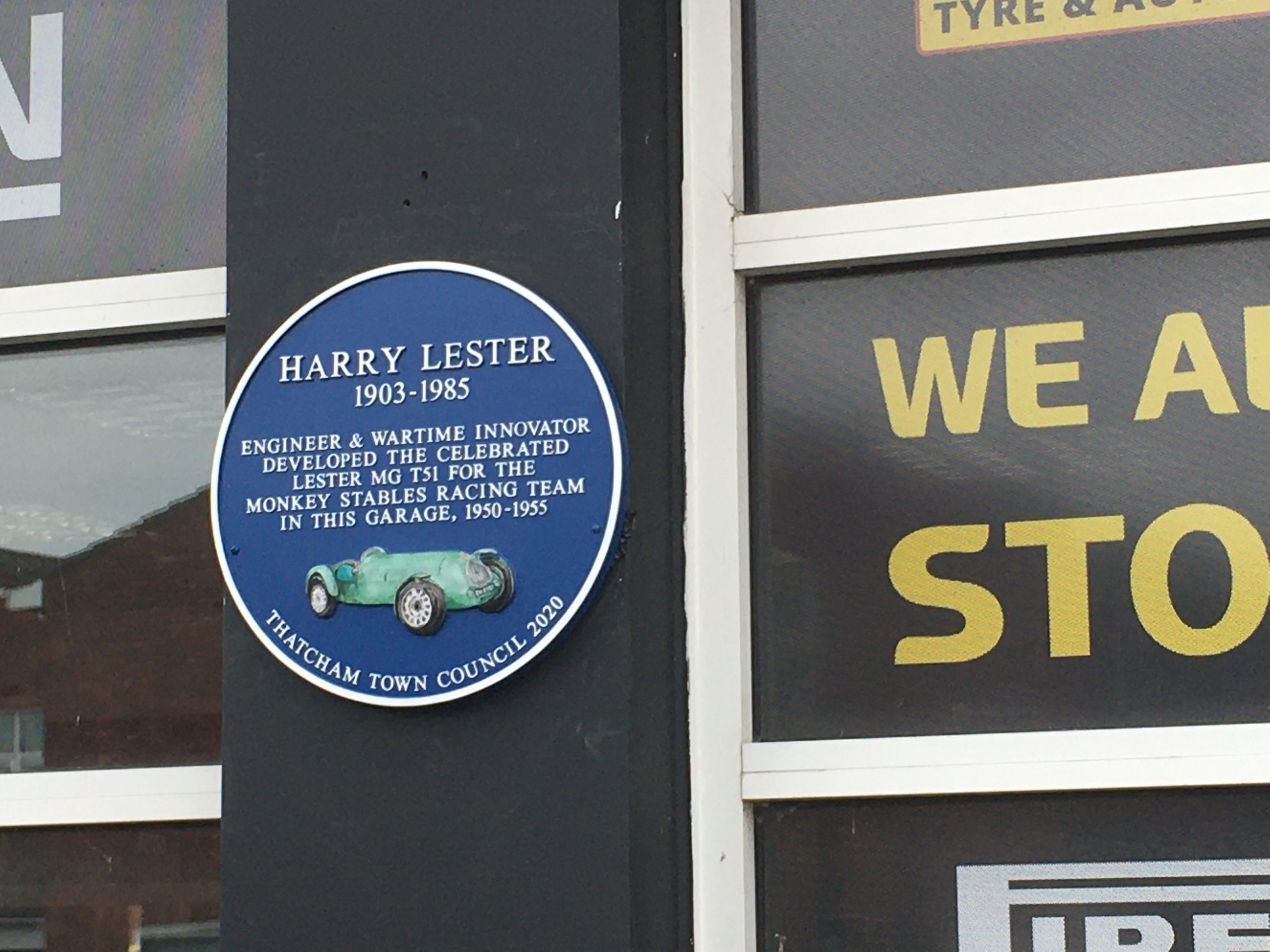 A photo of the blue plaque on the side of the garage on the Bath Road A4. It reads: Harry Lester. 1903 - 1985. Engineer and wartime innovator developed the celebrated Lester MGT51 for the Monkey Stables Racing team in this garage, 1950 - 1955.