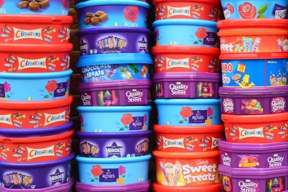 Four stacks of plastic tubs - celebrations, Quality Street, Roses, Haribo and Chocolate Treats.